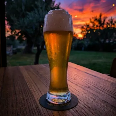 Un bicchiere alto e freddo di birra pilsner artigianale dorata con schiuma bianca